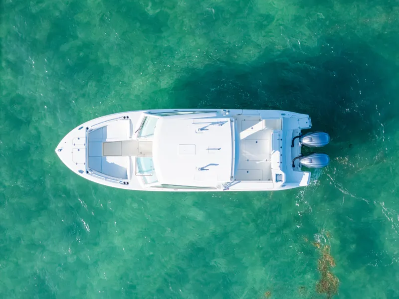 Slide: The Image of Aerial view of 2024 Cobia 330 Dual Console boat on clear turquoise water. - 18