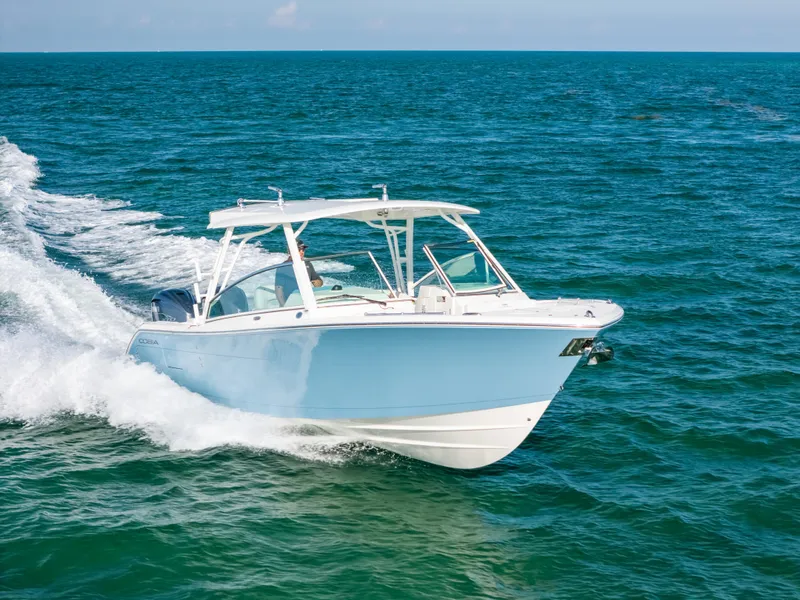 Slide: The Image of 2024 Cobia 330 Dual Console boat cruising on open ocean waters. - 23