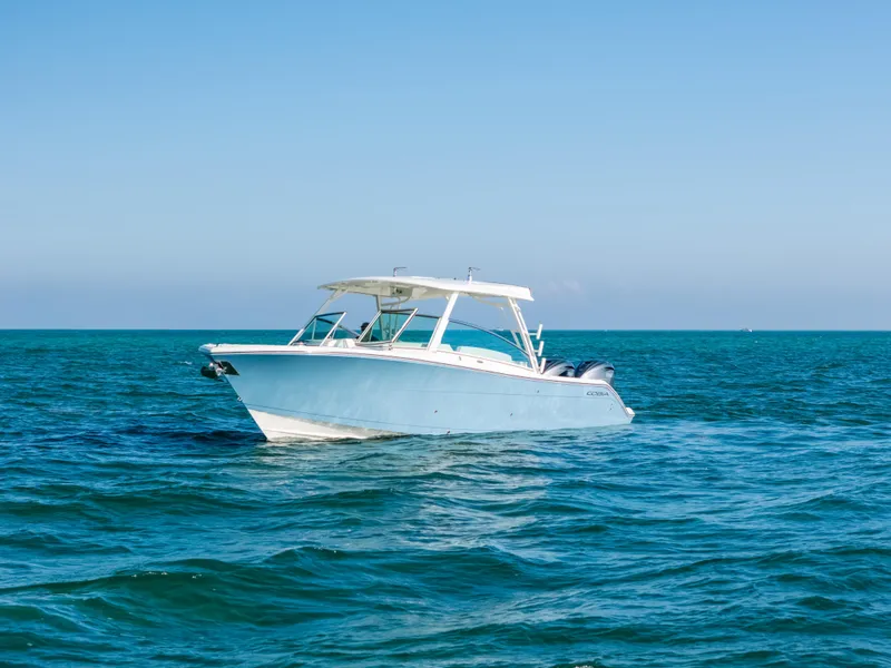 Slide: The Image of 2024 Cobia 330 Dual Console boat on open sea under clear blue sky. - 24