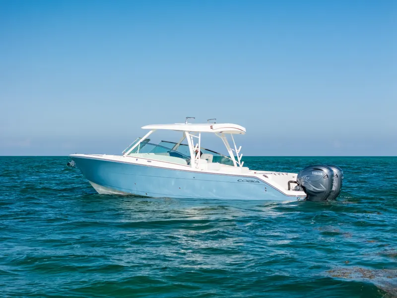 Slide: The Image of 2024 Cobia 330 Dual Console boat on open water, clear blue sky. - 25