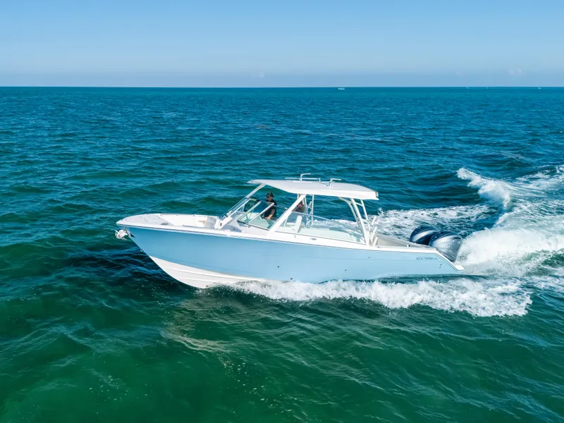 Slide: The Image of 2024 Cobia 330 Dual Console boat cruising on open ocean waters. - 26