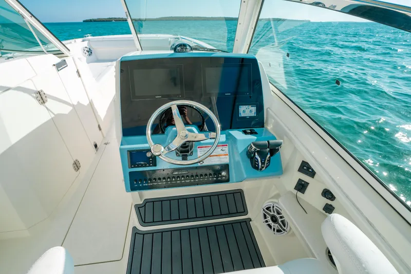 Slide: The Image of 2024 Cobia 330 Dual Console helm with ocean view, featuring modern controls and steering wheel. - 3