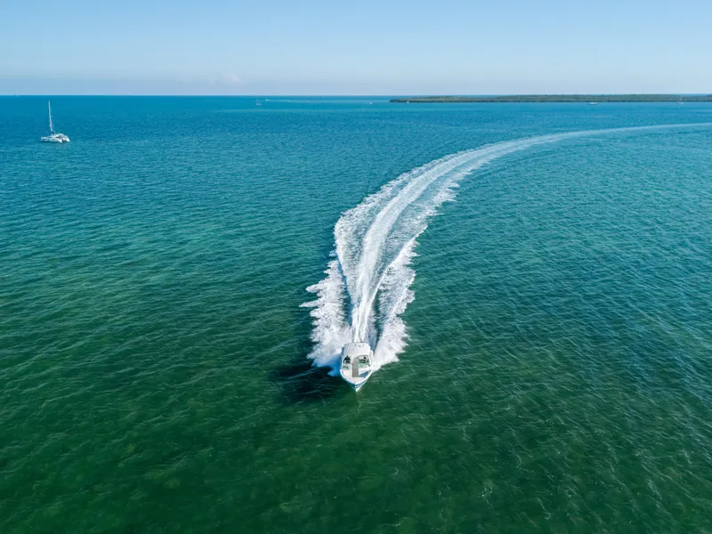 Slide: The Image of 2024 Cobia 330 Dual Console cruising on open sea, leaving a wake trail. - 30