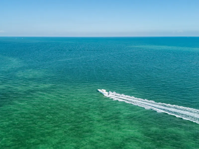 Slide: The Image of Aerial view of 2024 Cobia 330 Dual Console speeding across turquoise ocean waters. - 31
