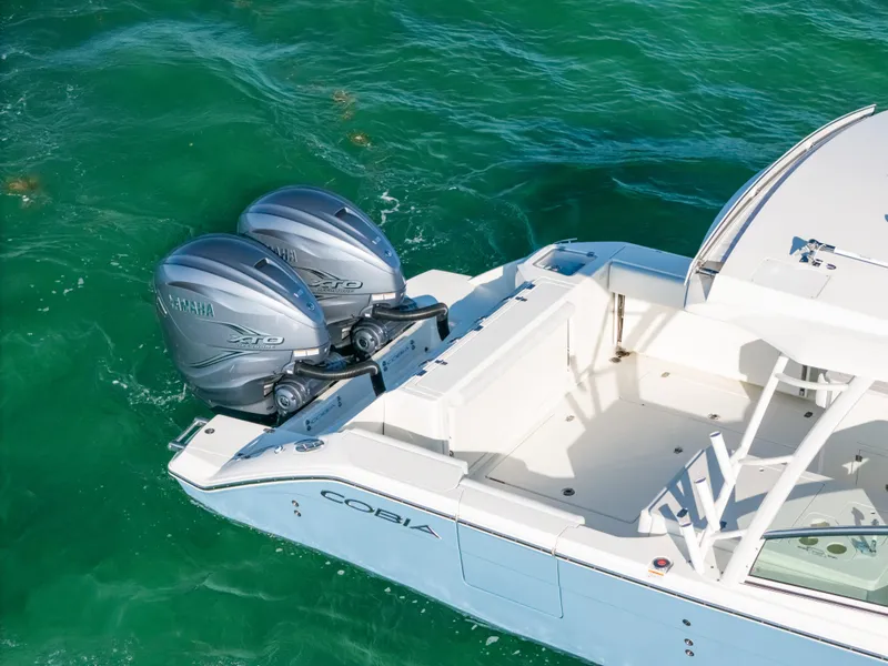 Slide: The Image of 2024 Cobia 330 Dual Console boat with twin Yamaha engines on turquoise water. - 8