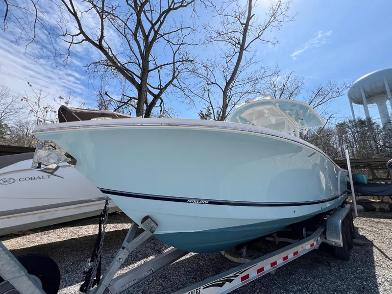 Slide: The Image of 2019 Regulator 28 boat on trailer under clear blue sky. - 0