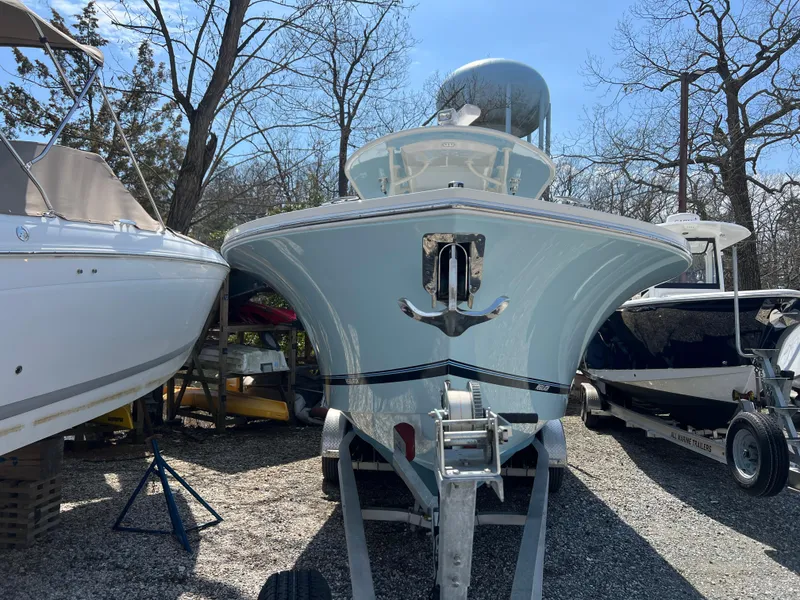 Slide: The Image of 2019 Regulator 28 boat on trailer, parked between other boats, in a wooded area. - 1