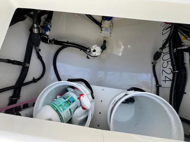 Slide: The Image of 2019 Regulator 28 boat storage compartment with cleaning supplies and visible wiring. - 13