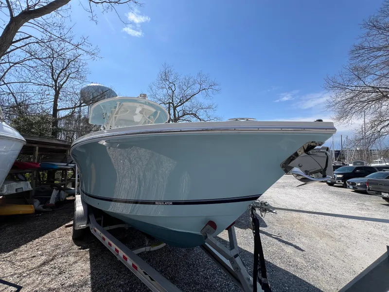 Slide: The Image of 2019 Regulator 28 boat on trailer, parked outdoors under clear blue sky. - 2
