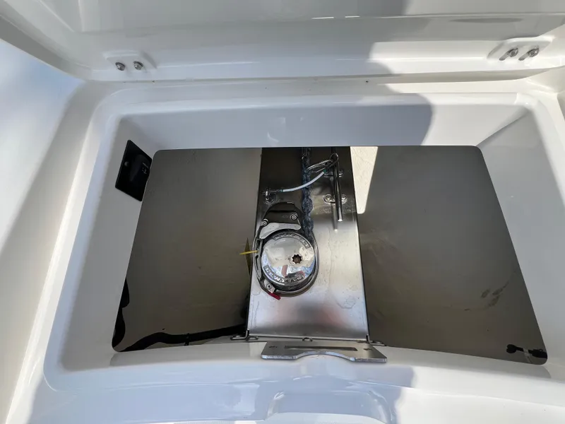 Slide: The Image of Open storage compartment on a 2019 Regulator 28 boat, featuring a metal latch and clean interior. - 26