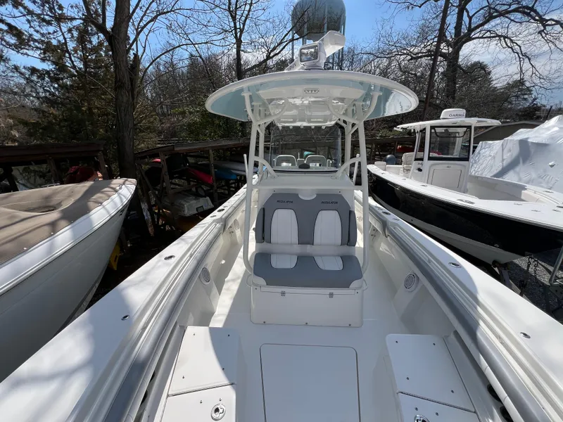Slide: The Image of 2019 Regulator 28 boat with dual seating, parked among trees and other boats. - 28