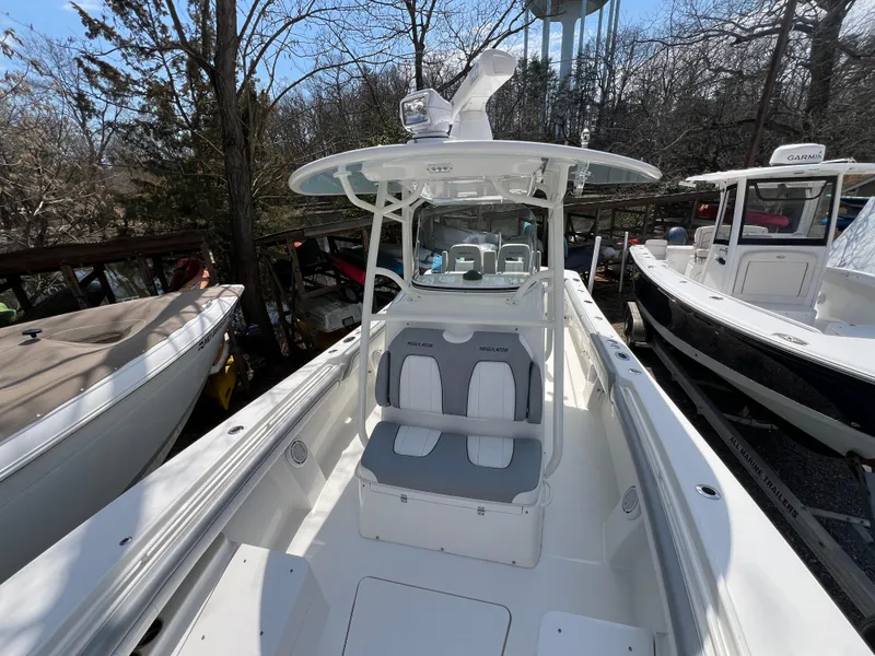 Slide: The Image of 2019 Regulator 28 boat with dual seats, parked among trees and other boats. - 29