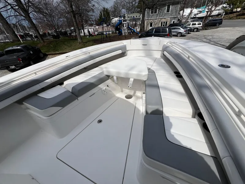 Slide: The Image of 2019 Regulator 28 boat interior with cushioned seating and table, parked outdoors. - 36