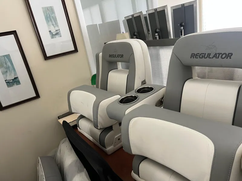 Slide: The Image of 2019 Regulator 28 boat seats with cup holders, indoors near framed artwork. - 44