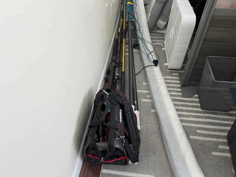 Slide: The Image of Fishing rods and gear bag stored indoors, next to a fan and rolled-up mat. - 45