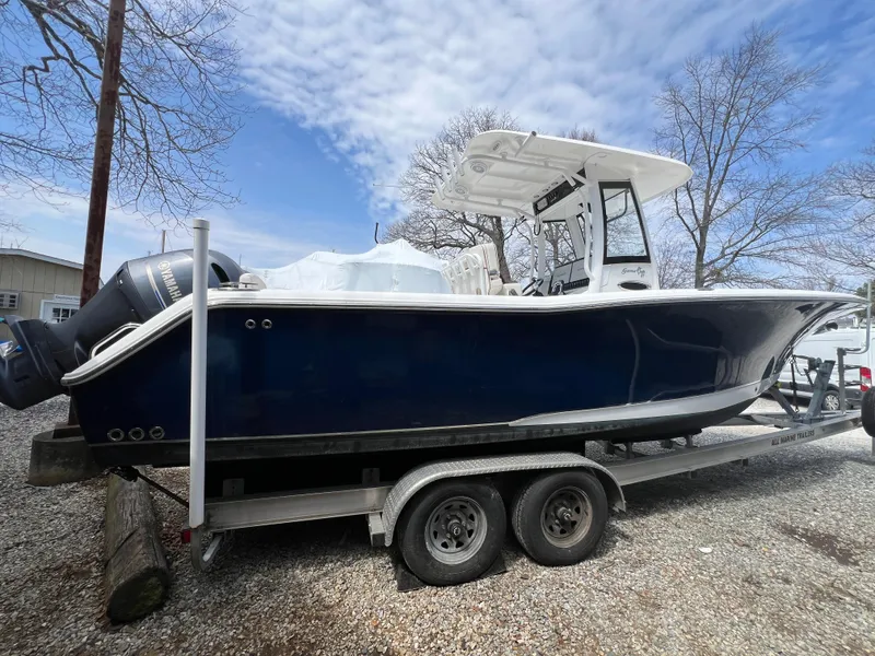 Slide: The Image of 2020 Sea Hunt Gamefish 27 boat on trailer, blue hull, parked outdoors. - 3