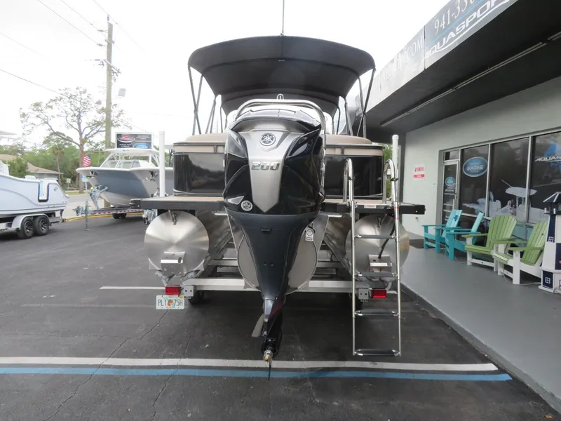 Slide: The Image of 2025 Avalon LSZ Quad Lounger pontoon boat with outboard motor, parked at dealership. - 14