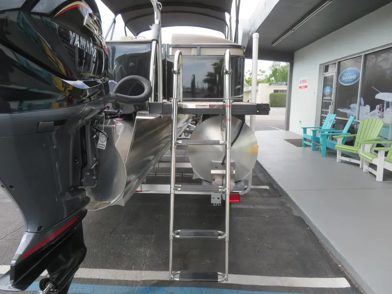 Slide: The Image of 2025 Avalon LSZ Quad Lounger pontoon boat with Yamaha motor and ladder, parked outside a showroom. - 15