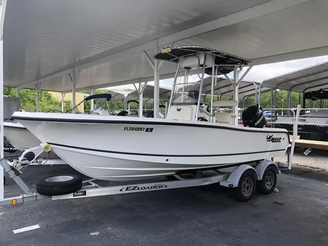 Slide: The Image of 2009 Mako 204 Center Console boat with Suzuki outboard motor, parked in a marina. - 4