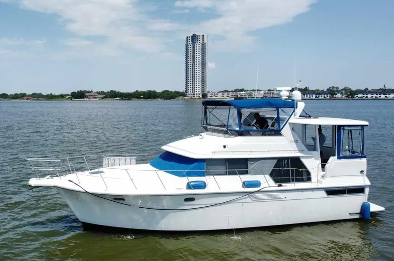 Slide: The Image of 1995 Carver 440 Aft Cabin Motor Yacht on calm water with cityscape background. - 1