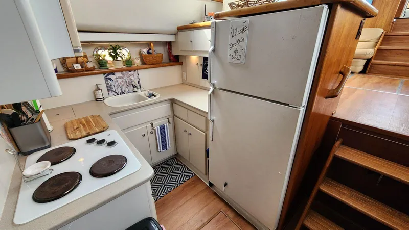 Slide: The Image of 1995 Carver 440 Aft Cabin Motor Yacht kitchen with stove, fridge, and wooden accents. - 30