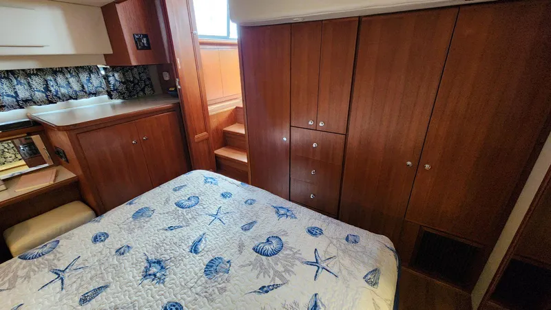 Slide: The Image of 1995 Carver 440 Aft Cabin Motor Yacht interior with wood cabinetry and nautical-themed bedding. - 38