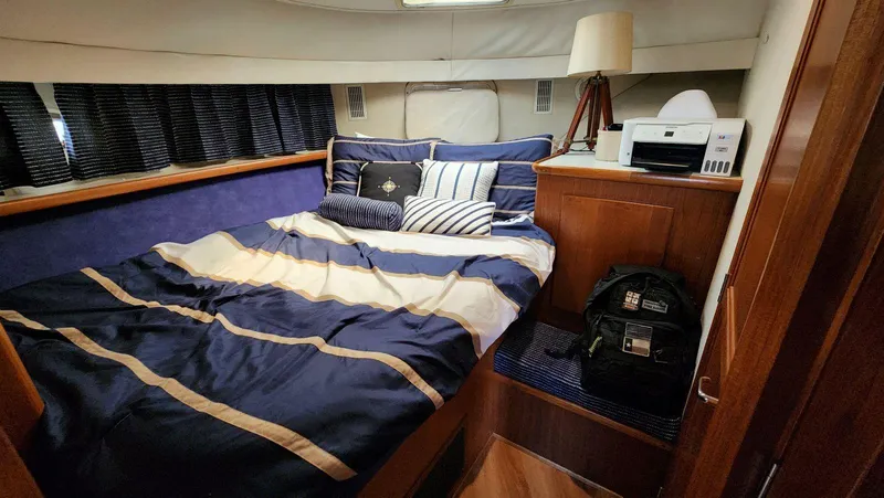 Slide: The Image of Cozy bedroom in 1995 Carver 440 Aft Cabin Motor Yacht with striped bedding and wooden cabinetry. - 42