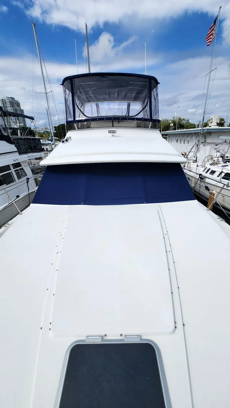 Slide: The Image of 1995 Carver 440 Aft Cabin Motor Yacht docked, featuring spacious deck and blue canopy. - 8
