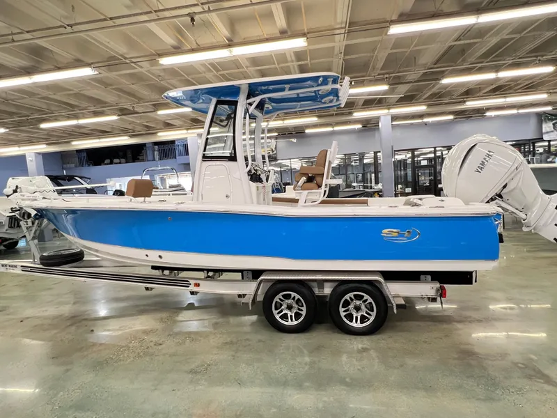 Slide: The Image of 2022 Sea Hunt BX25FS boat with blue hull on trailer in showroom. - 1