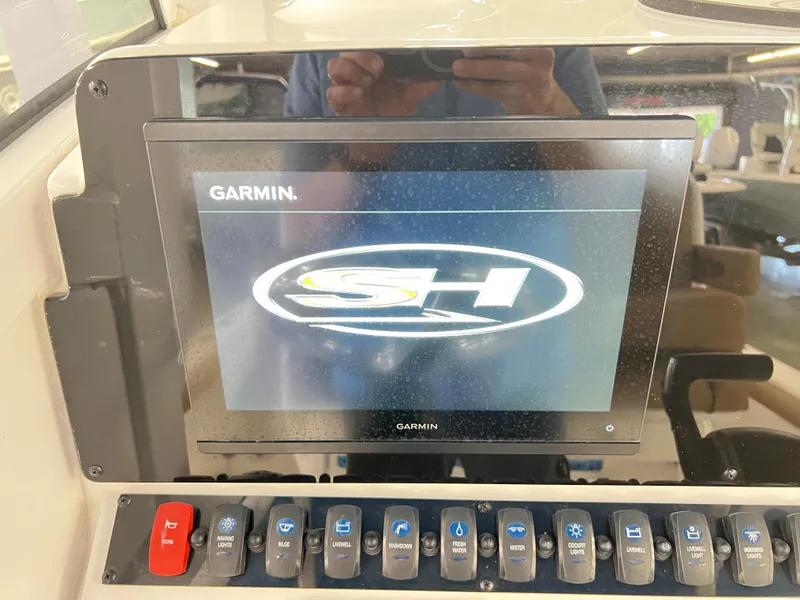 Slide: The Image of Garmin display on 2022 Sea Hunt BX25FS boat dashboard with control switches. - 13
