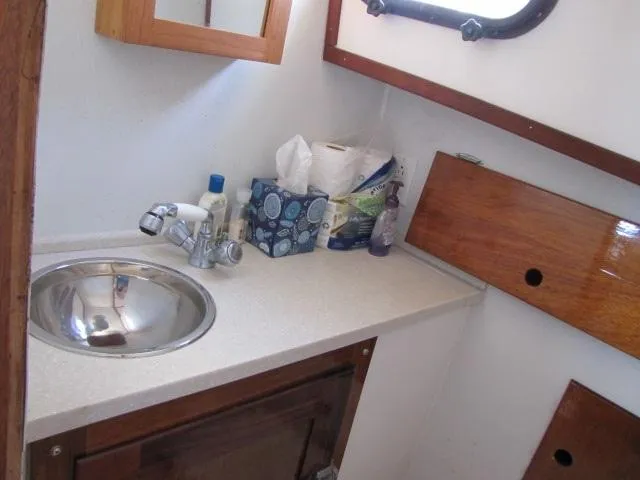 Slide: The Image of 1974 Custom Lazy Jack 32 boat bathroom with sink, toiletries, and wooden cabinetry. - 19