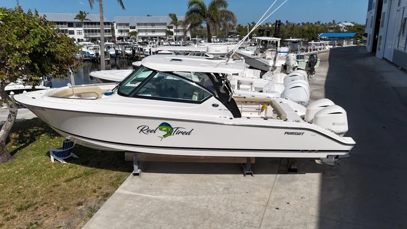 Slide: The Image of 2016 Pursuit DC 295 Dual Console boat with twin Yamaha 300 engines docked at marina. - 2