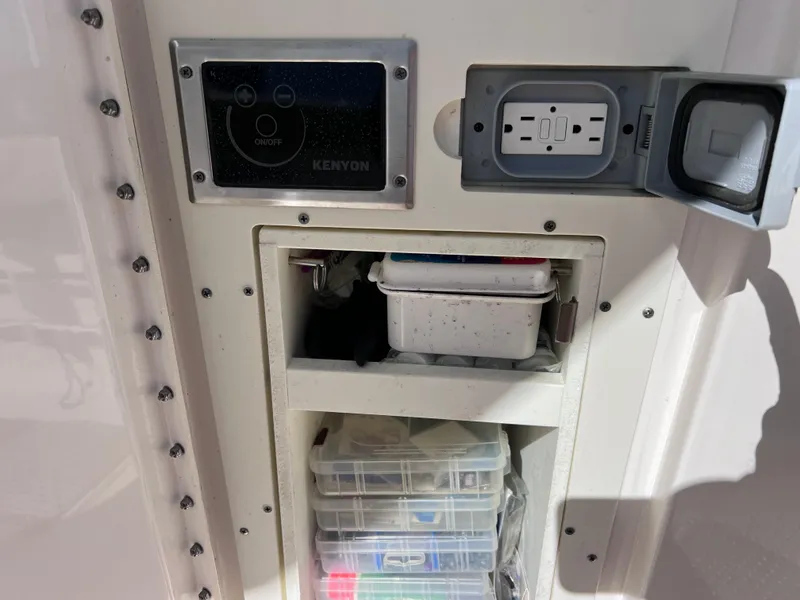 Slide: The Image of Storage compartment on a 2016 Pursuit DC 295 boat with electrical outlet and control panel. - 39