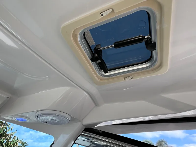 Slide: The Image of 2016 Pursuit DC 295 boat interior with open hatch and speaker, showcasing clean design. - 44