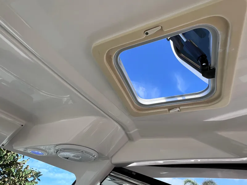 Slide: The Image of 2016 Pursuit DC 295 boat interior with open sunroof, showcasing clear blue sky. - 45