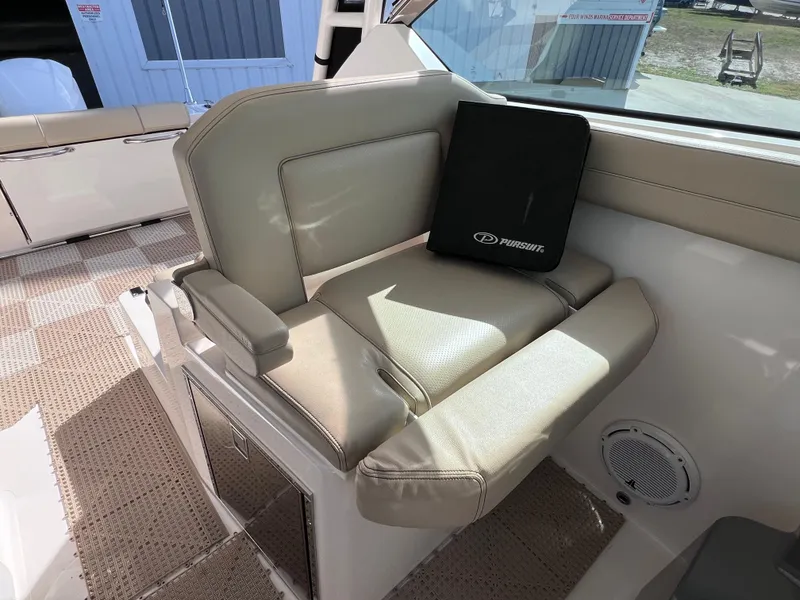 Slide: The Image of 2016 Pursuit DC 295 boat interior with beige seating and storage compartment. - 46