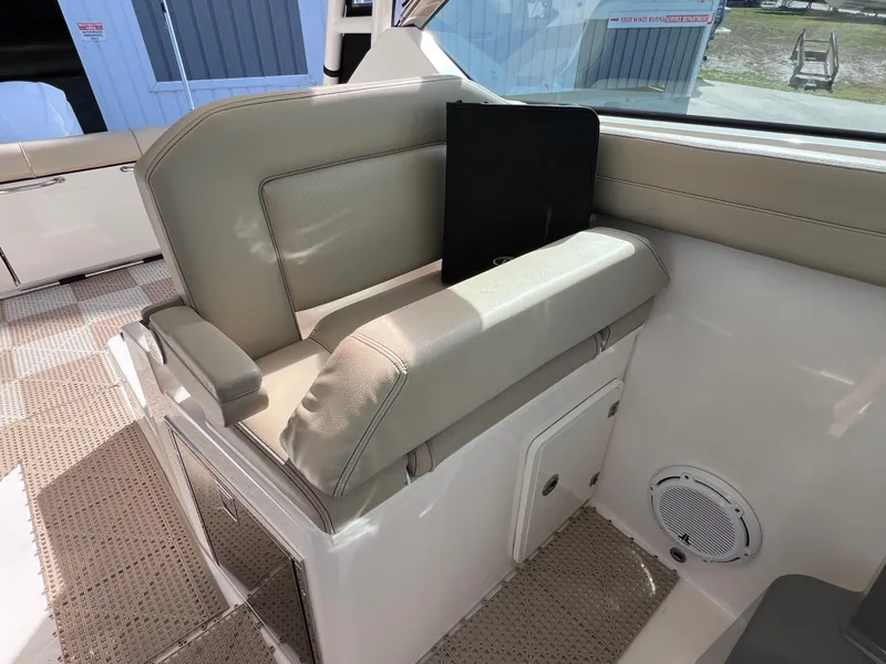 Slide: The Image of 2016 Pursuit DC 295 boat interior with beige seating and storage compartment. - 47