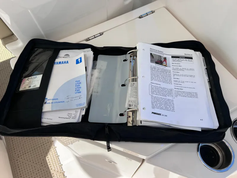 Slide: The Image of Open binder with manuals for 2016 Pursuit DC 295 boat, featuring Yamaha engines. - 48