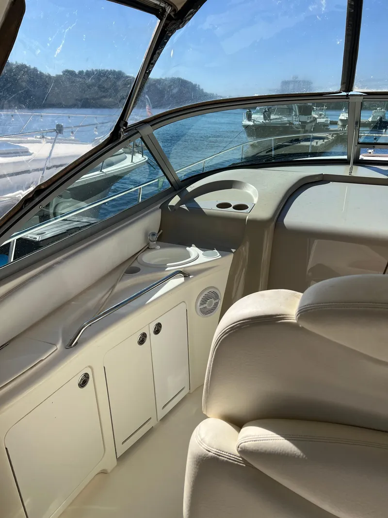 Slide: The Image of 1999 Sea Ray 340 Sundancer interior with beige seating and cabinetry, overlooking a serene water view. - 5