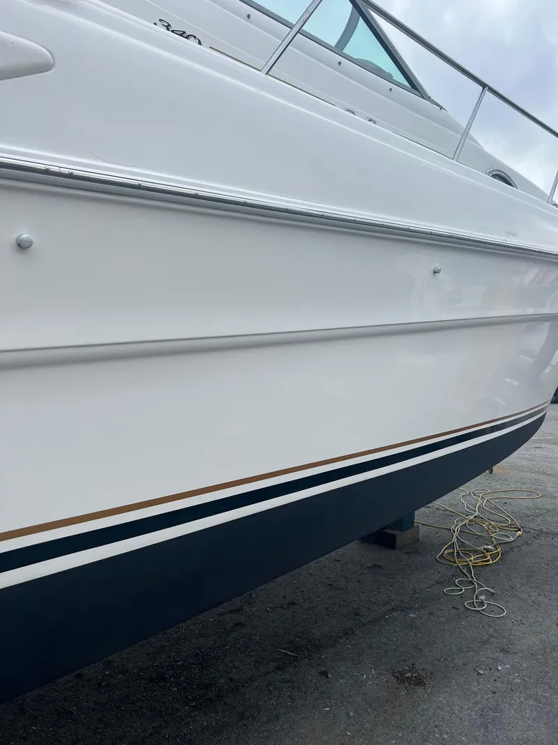 Slide: The Image of 1999 Sea Ray 340 Sundancer boat hull, white with blue and gold trim, docked. - 6