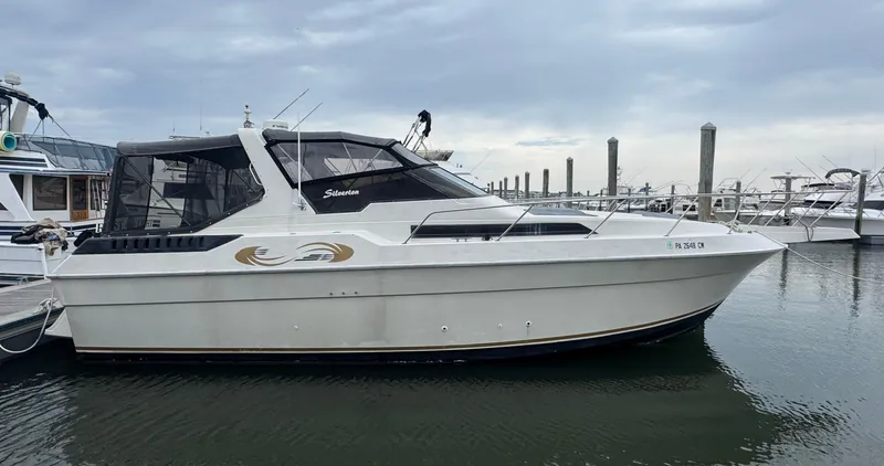 Slide: The Image of 1987 Silverton Express boat docked at marina under cloudy sky. - 0