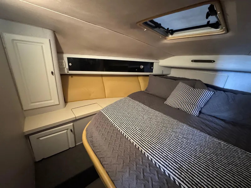 Slide: The Image of 1987 Silverton Express cabin interior with cozy bed and striped bedding. - 11