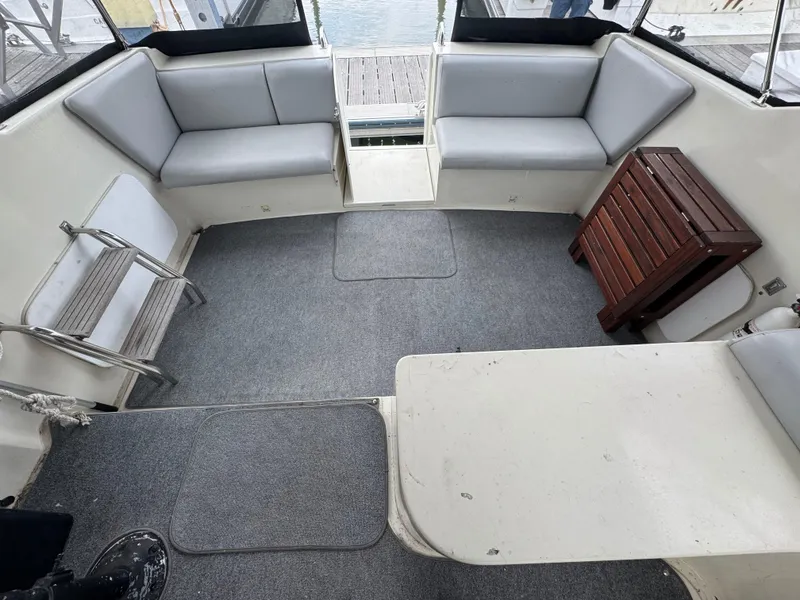 Slide: The Image of 1987 Silverton Express boat interior with gray seating, carpet, and wooden table. - 5