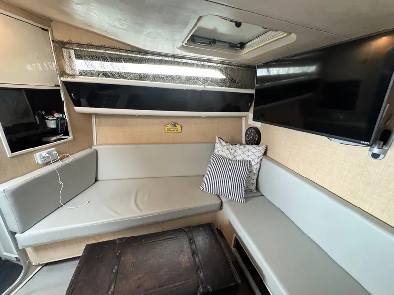 Slide: The Image of 1987 Silverton Express boat interior with seating, pillows, TV, and storage. - 7