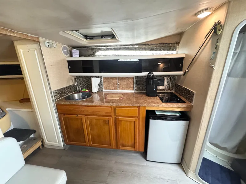Slide: The Image of 1987 Silverton Express boat interior with kitchenette, featuring wood cabinets, sink, and mini fridge. - 8