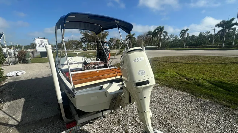 Slide: The Image of 1971 Boston Whaler 13 Sport boat with outboard motor, parked on gravel near palm trees. - 3