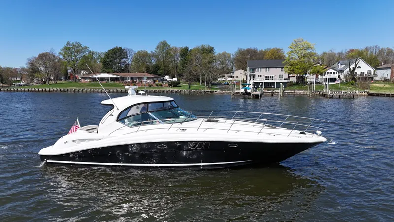 Slide: The Image of 2007 Sea Ray 44 Sundancer yacht cruising on a scenic river with waterfront homes. - 0