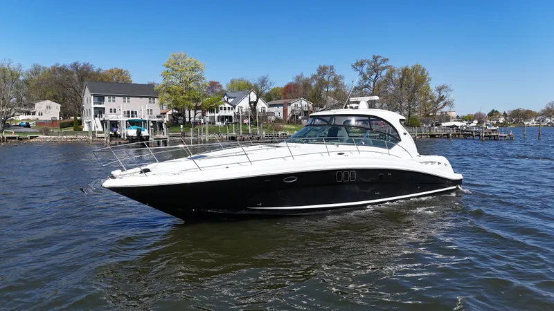 Slide: The Image of 2007 Sea Ray 44 Sundancer yacht cruising on a scenic waterfront with houses in the background. - 8