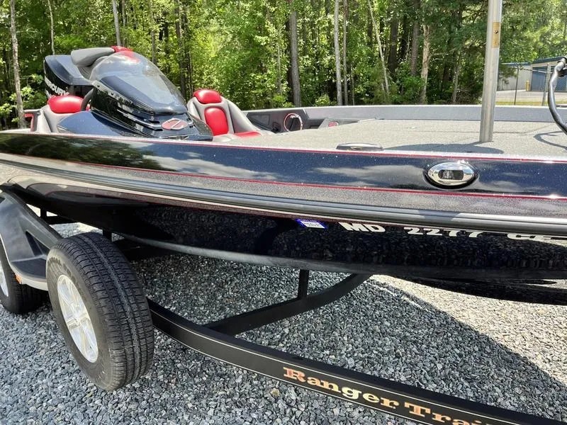 Slide: The Image of 2014 Ranger Z118 Comanche boat on trailer, parked on gravel, surrounded by trees. - 1