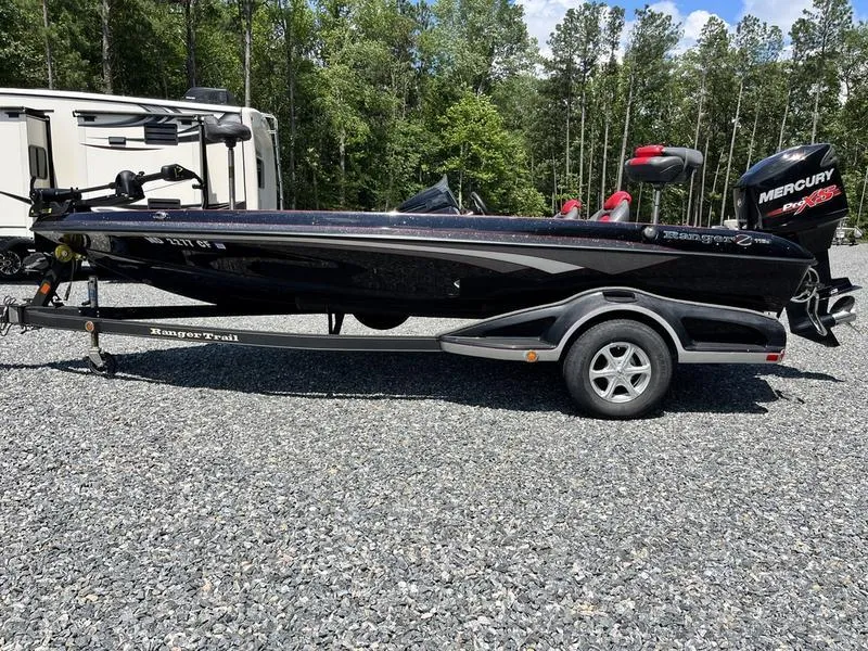 Slide: The Image of 2014 Ranger Z118 Comanche boat on trailer, parked outdoors with trees in background. - 21